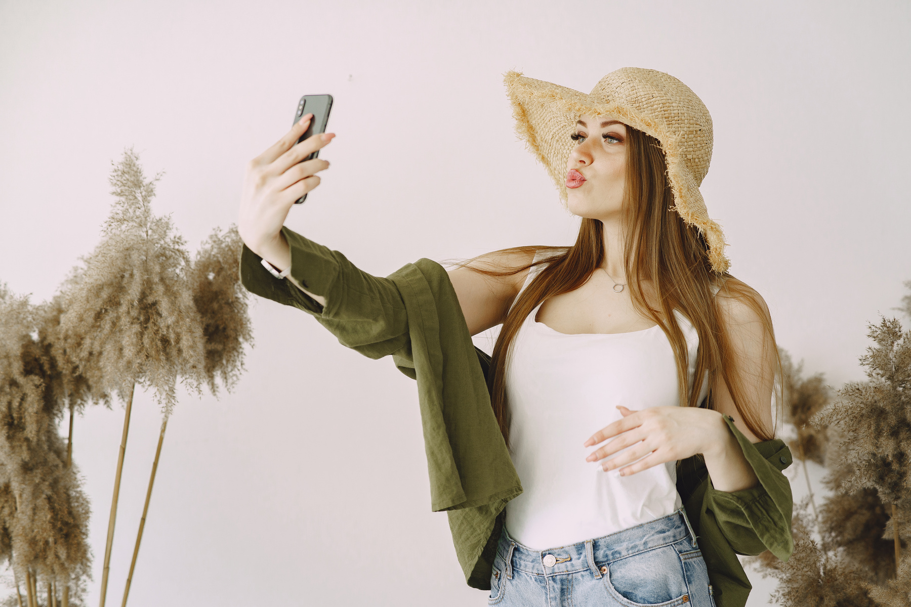Cool young woman in straw hat taking self portrait with duck face